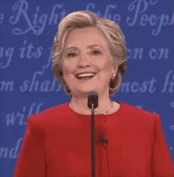 a woman in a red dress is smiling in front of a sign that says ' freedom of the people '