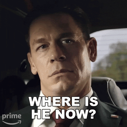 a man in a suit and tie is sitting in a car and asking where is he now