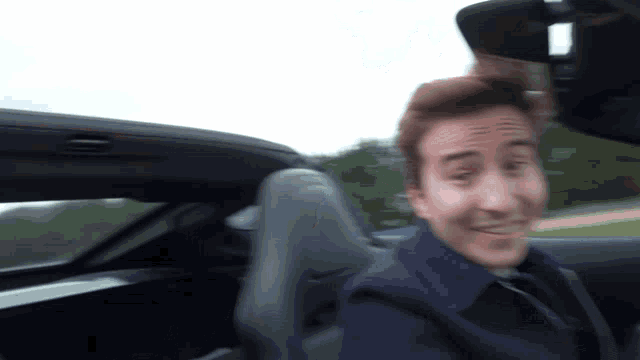 a man in a blue jacket is sitting in a car