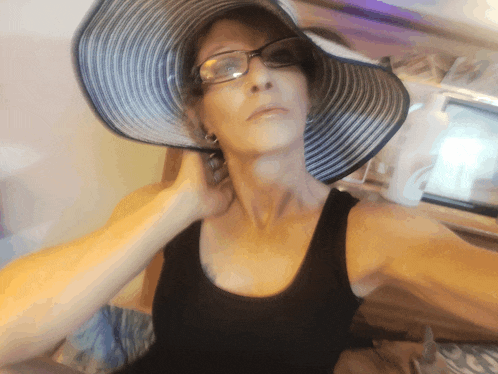 a woman wearing a black tank top and a large hat