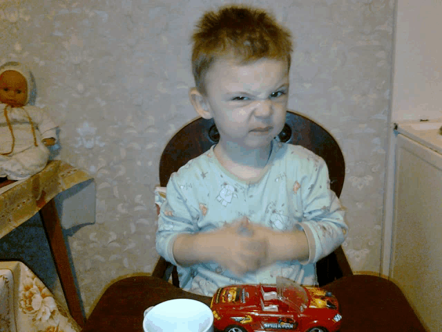a little boy is sitting in a high chair with a toy car that says thunderbolt