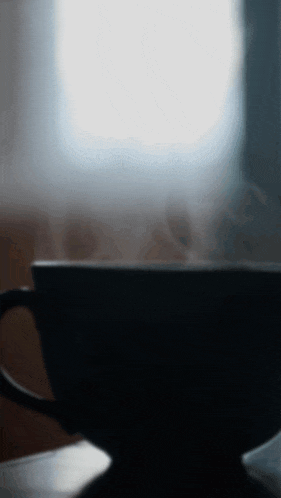 a cup of coffee with steam coming out of it is on a table