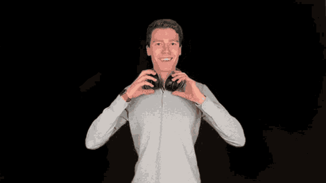 a man wearing headphones against a black background is smiling