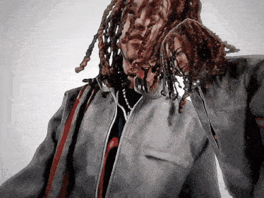 a man with dreadlocks is wearing a grey jacket and a black shirt