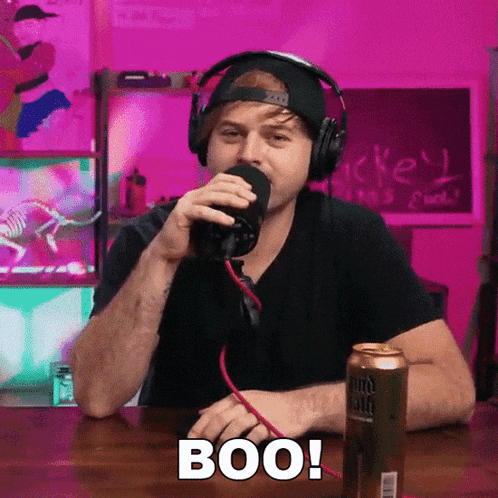 a man wearing headphones is sitting at a table with a can of bud light in front of him and says boo