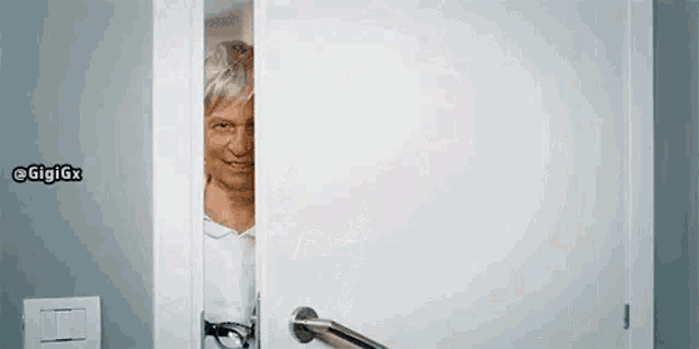 an elderly woman is peeking out of a doorway .