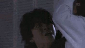 a man and a woman are standing next to each other in a dark room and talking to each other .