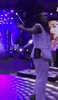 a woman is standing on a stage with a microphone in her hand and a purple background .