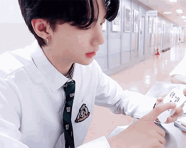 a boy wearing a white shirt and tie is holding a piece of paper that says object