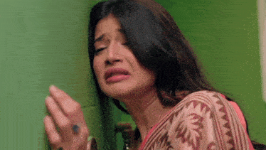 a woman is crying while leaning against a wall .