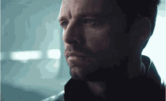 a close up of a man 's face with a beard and a black jacket .