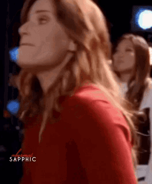 a woman in a red shirt is standing in front of a crowd of people .
