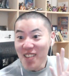 a man with a shaved head is wearing ear buds and waving