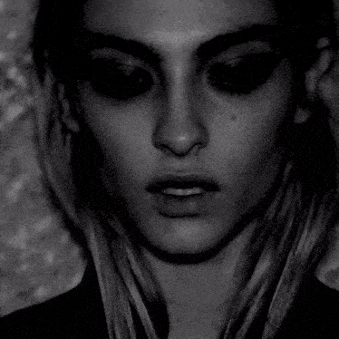 a black and white photo of a woman 's face with dark eye makeup