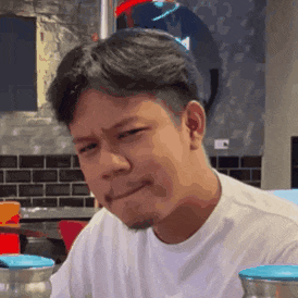 a man is making a funny face while sitting at a table .