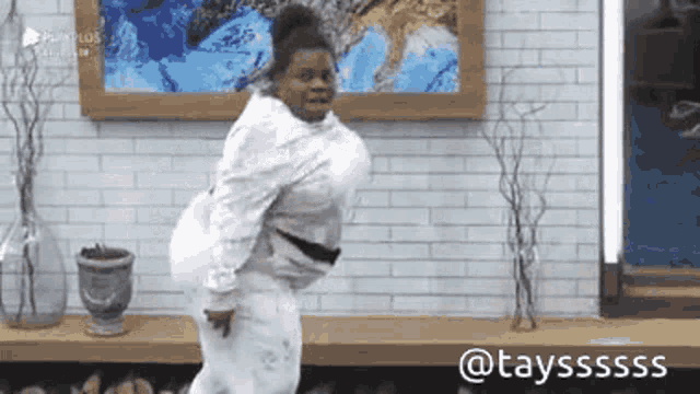 a woman in a white sweater is dancing in a room with a painting on the wall .