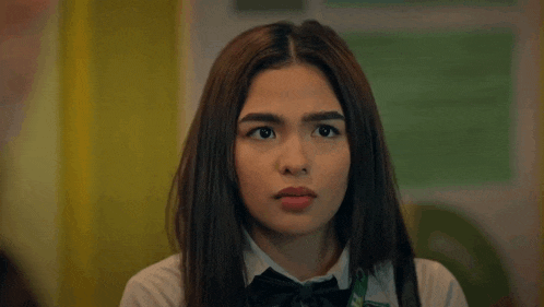a girl in a bow tie looks at the camera with a serious look on her face