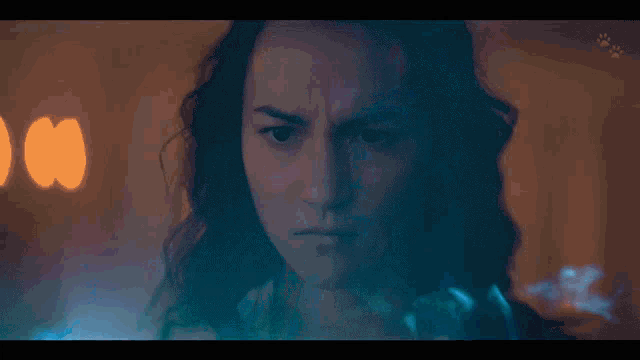 a close up of a woman 's face with a blue light behind her