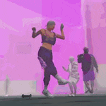 a woman is dancing in front of a pink wall while a man and a child are standing behind her .
