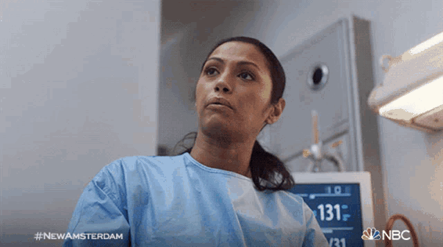 a woman stands in front of a monitor that says 131 on it
