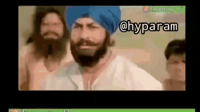 a man with a beard and a blue turban is standing in front of a group of men .