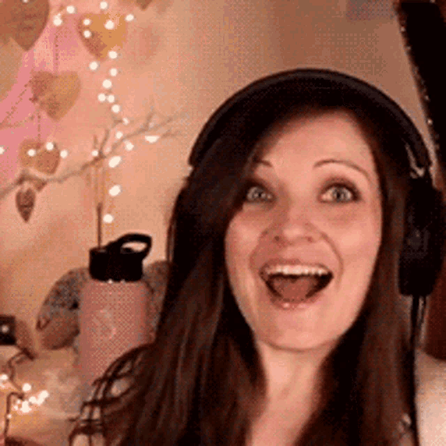 a woman is wearing headphones and smiling with her mouth open