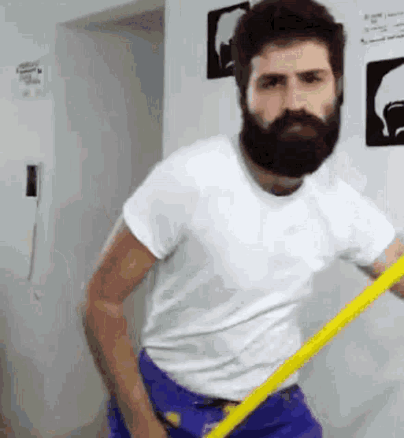 a man with a beard and a white shirt is holding a yellow mop .
