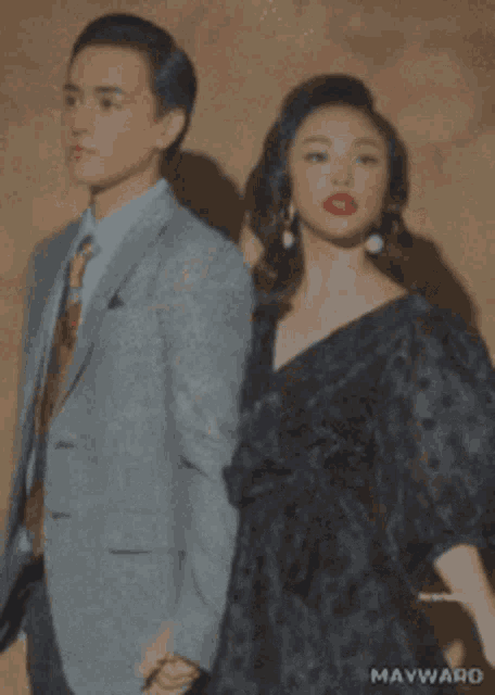 a man in a suit and tie and a woman in a black dress are standing next to each other