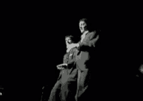 a couple of men in suits are standing next to each other on a stage .