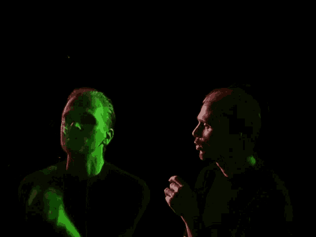 a man in a black shirt stands in front of a green and red light