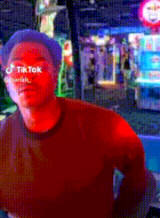 a man with tiktok written on his face stands in front of an arcade