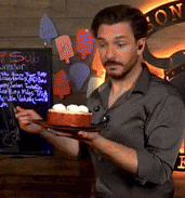 a man is holding a plate of food in front of a sign that says " sub "