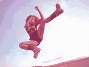 a woman is jumping in the air with her leg up in the air