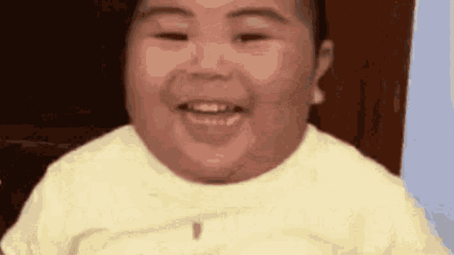 a close up of a baby making a funny face while smiling .