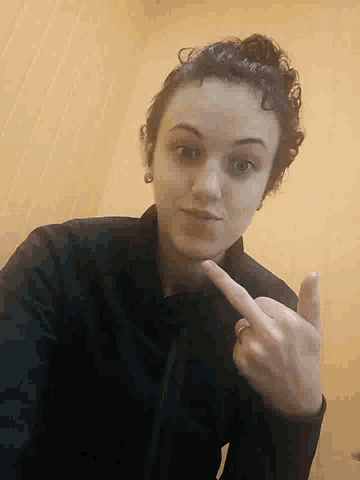 a woman is giving the middle finger and pointing at herself