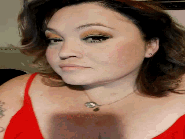 a close up of a woman 's face with a red top