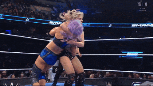 two women are wrestling in a ring with a banner that says smack