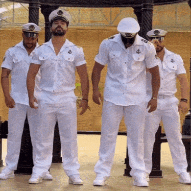 a group of men dressed in white uniforms and hats with anchors on them