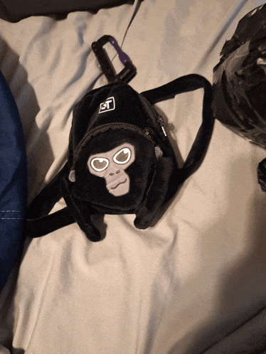 a small black bag with a gorilla face and the letter t on it