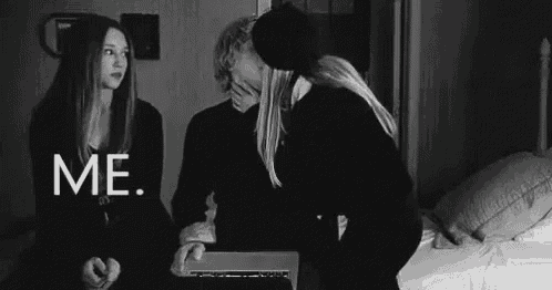 a black and white photo of a couple kissing while a woman watches .