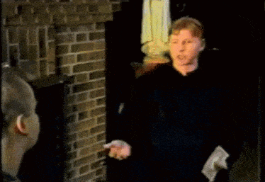 a man is standing in front of a brick wall and talking