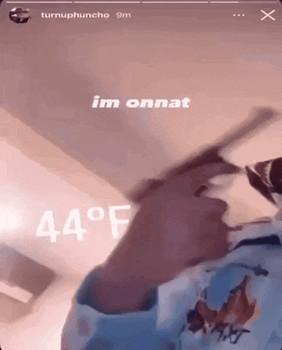 a person is holding a gun in front of a sign that says 44 degrees .