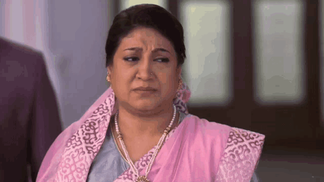 a woman wearing a pink scarf and pearls is making a funny face