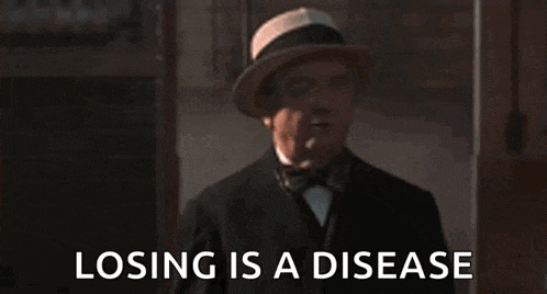 a man in a hat and bow tie is standing in front of a sign that says losing is a disease .
