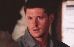 a man in a blue shirt is looking at the camera with a serious look on his face .
