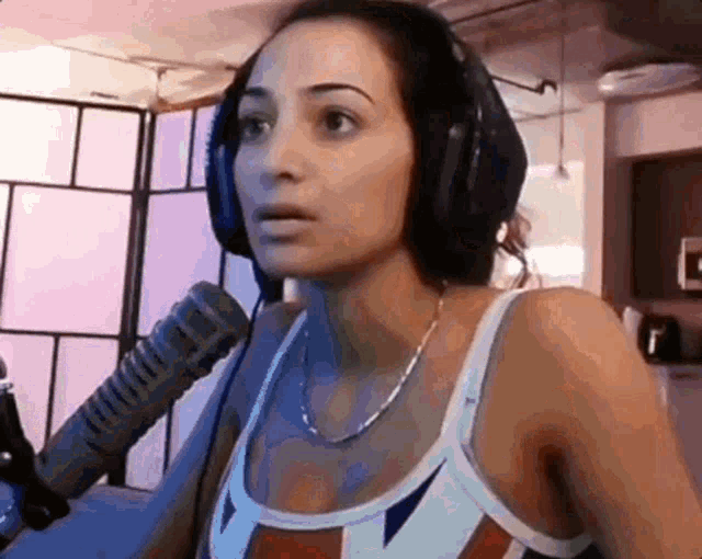 a woman wearing headphones is standing in front of a microphone .