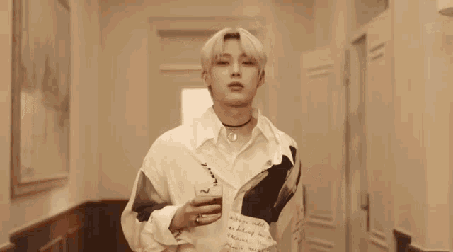 a man in a white shirt holds a glass in his hand
