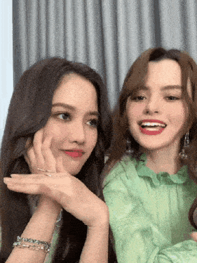 two women are sitting next to each other and one is wearing a green dress