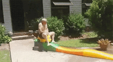 a naked man is sitting on a slide in a driveway