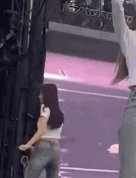 a woman in a white crop top and jeans is standing on a stage .